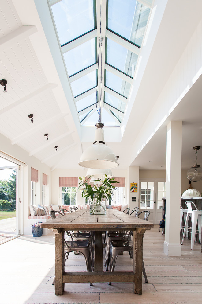 Immagine di una grande sala da pranzo aperta verso la cucina stile marino con pareti bianche e parquet chiaro
