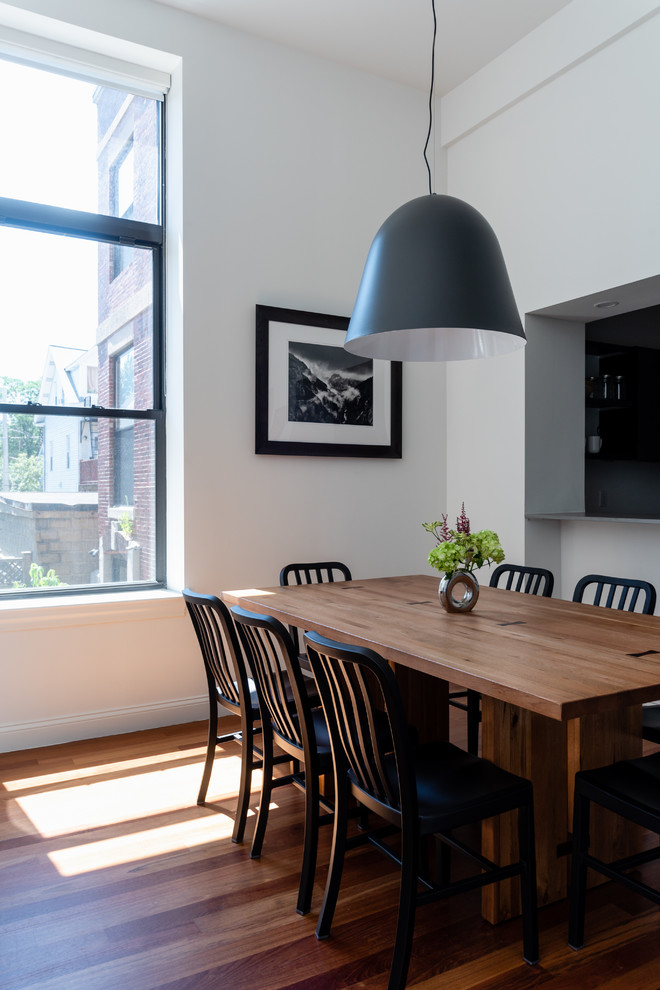 Esempio di una sala da pranzo aperta verso il soggiorno contemporanea di medie dimensioni con pareti bianche, pavimento in legno massello medio e pavimento marrone