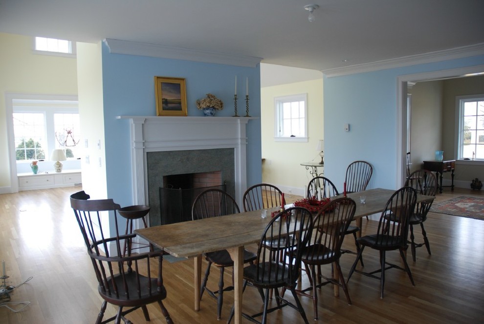 Large classic dining room in Providence with blue walls, light hardwood flooring, a standard fireplace and a wooden fireplace surround.