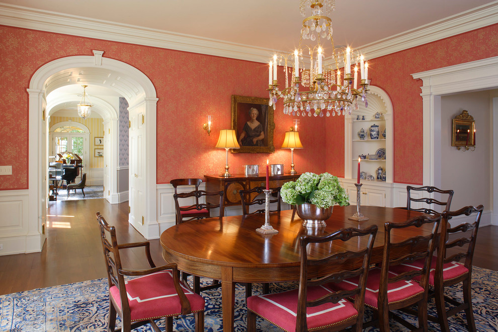 Idée de décoration pour une salle à manger tradition fermée avec un mur rouge, parquet foncé et éclairage.