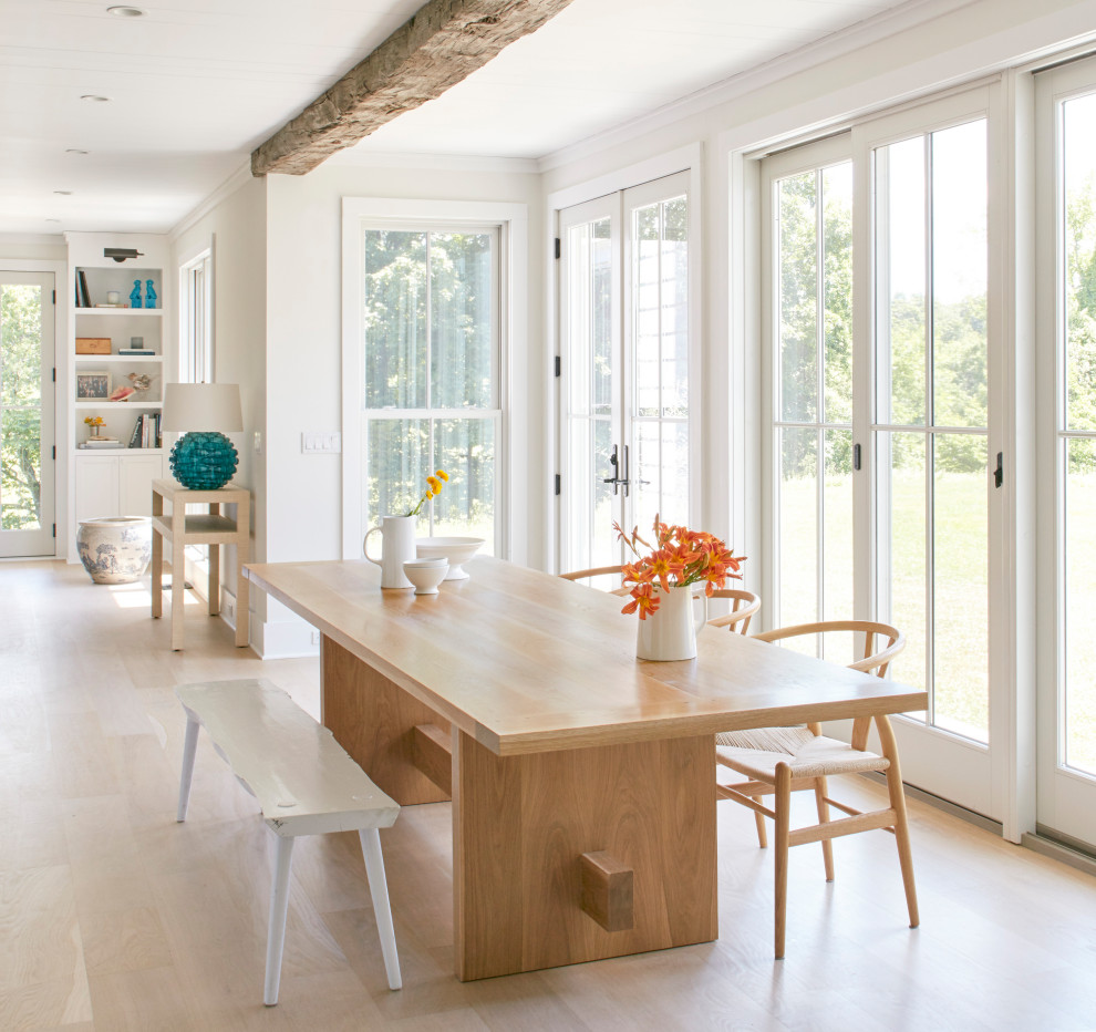 Example of a beach style light wood floor great room design in New York with white walls and no fireplace