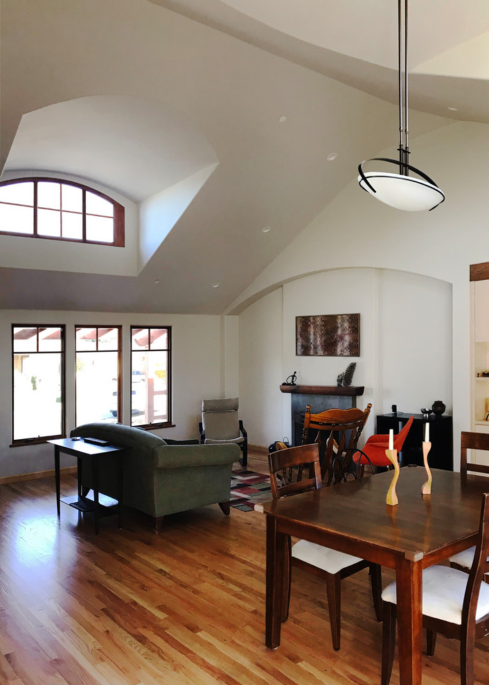 Cette image montre une salle à manger design avec un mur blanc, parquet clair, une cheminée standard et un manteau de cheminée en carrelage.