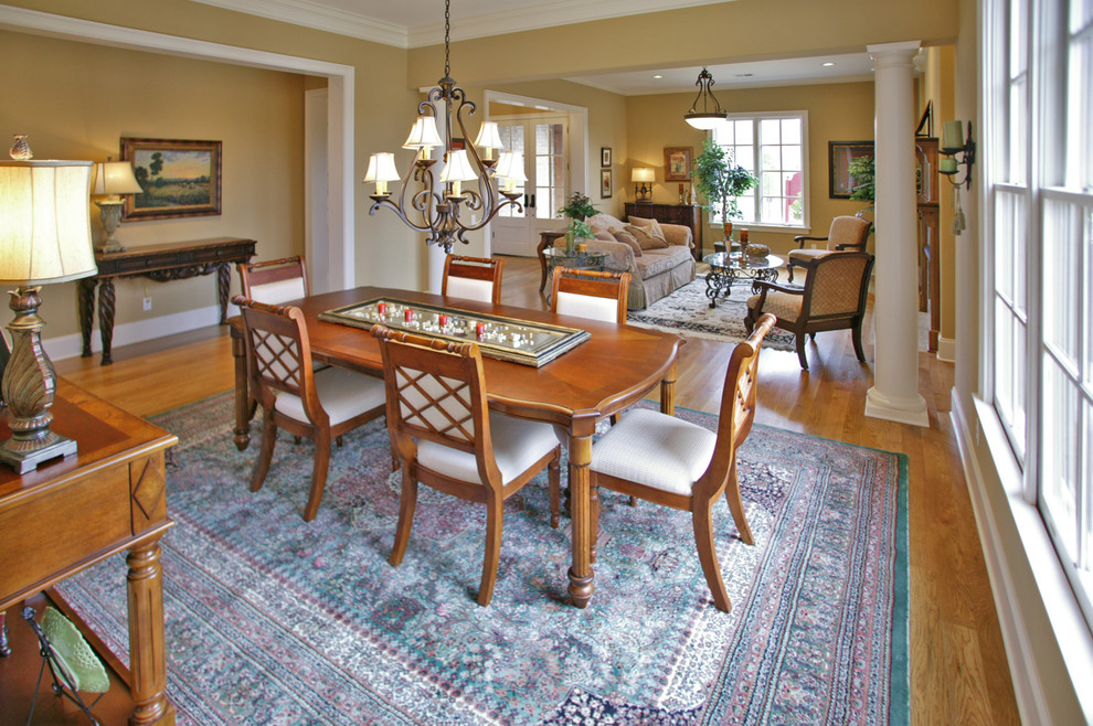 Immagine di una sala da pranzo aperta verso il soggiorno tradizionale di medie dimensioni con pareti beige, pavimento in legno massello medio e nessun camino