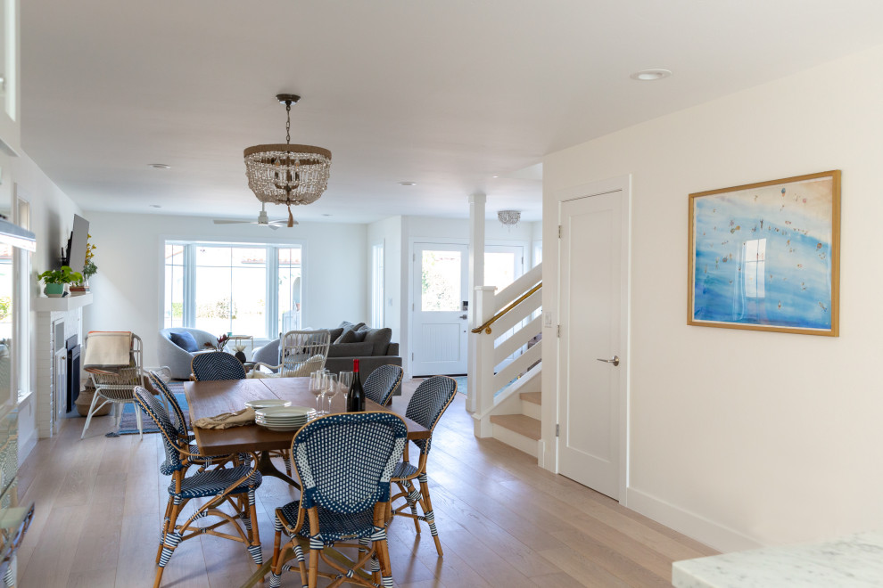 Esempio di una sala da pranzo aperta verso la cucina costiera di medie dimensioni con pareti bianche, parquet chiaro e pavimento beige