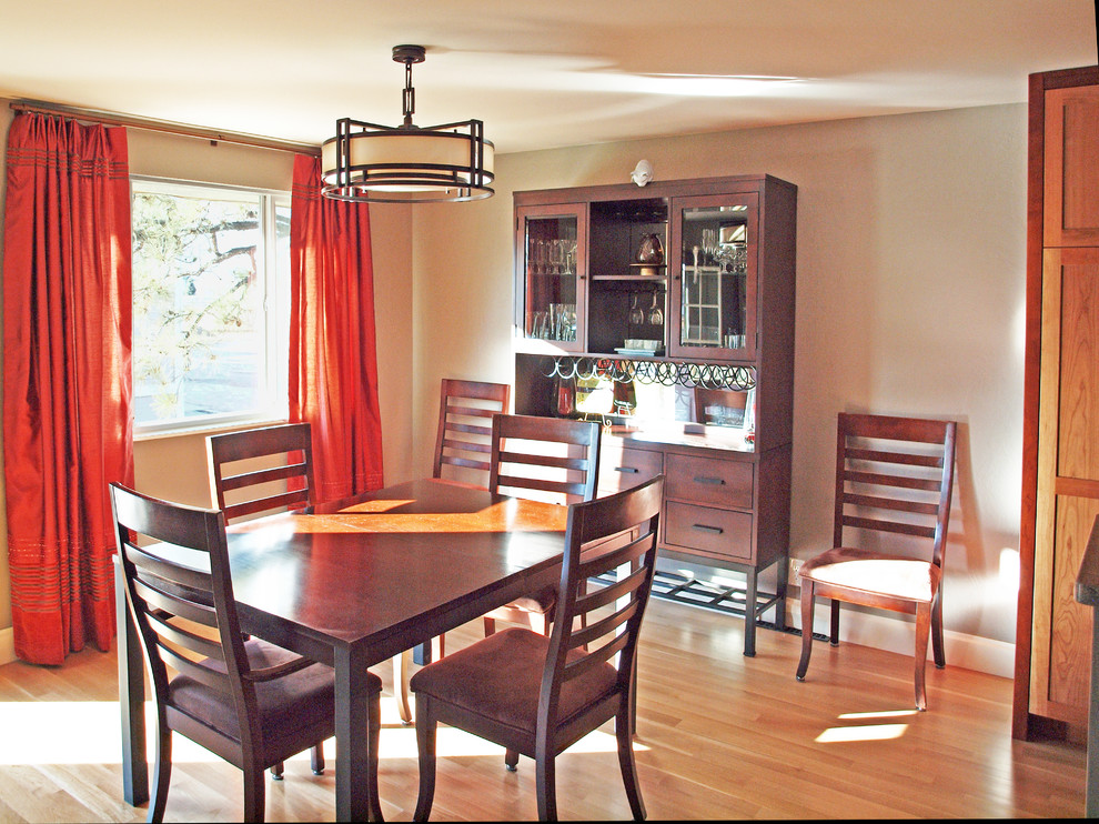 Inspiration pour une salle à manger ouverte sur le salon craftsman avec un mur gris, parquet clair, une cheminée standard, un manteau de cheminée en pierre et un sol jaune.