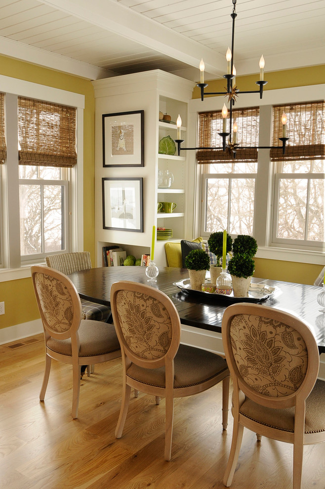 Idée de décoration pour une salle à manger champêtre avec un mur jaune et un sol en bois brun.