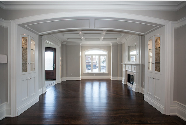 Large classic dining room in Toronto with beige walls, dark hardwood flooring, a standard fireplace and brown floors.