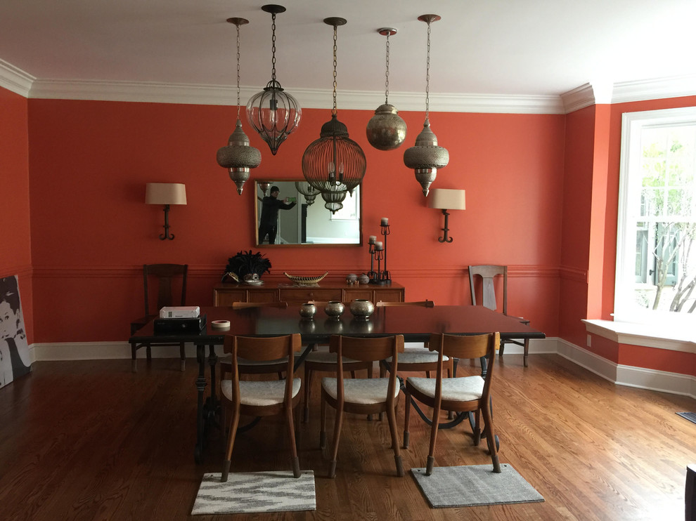 Réalisation d'une salle à manger tradition fermée et de taille moyenne avec un mur rouge, un sol en bois brun et aucune cheminée.