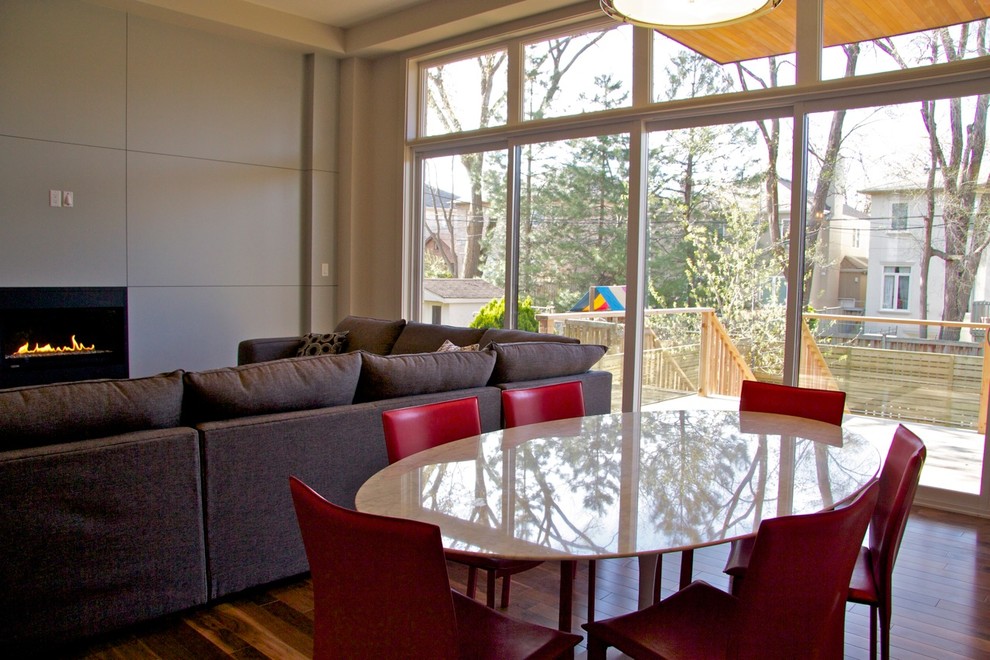 Cette photo montre une petite salle à manger ouverte sur le salon tendance avec un mur beige, un sol en bois brun et une cheminée ribbon.
