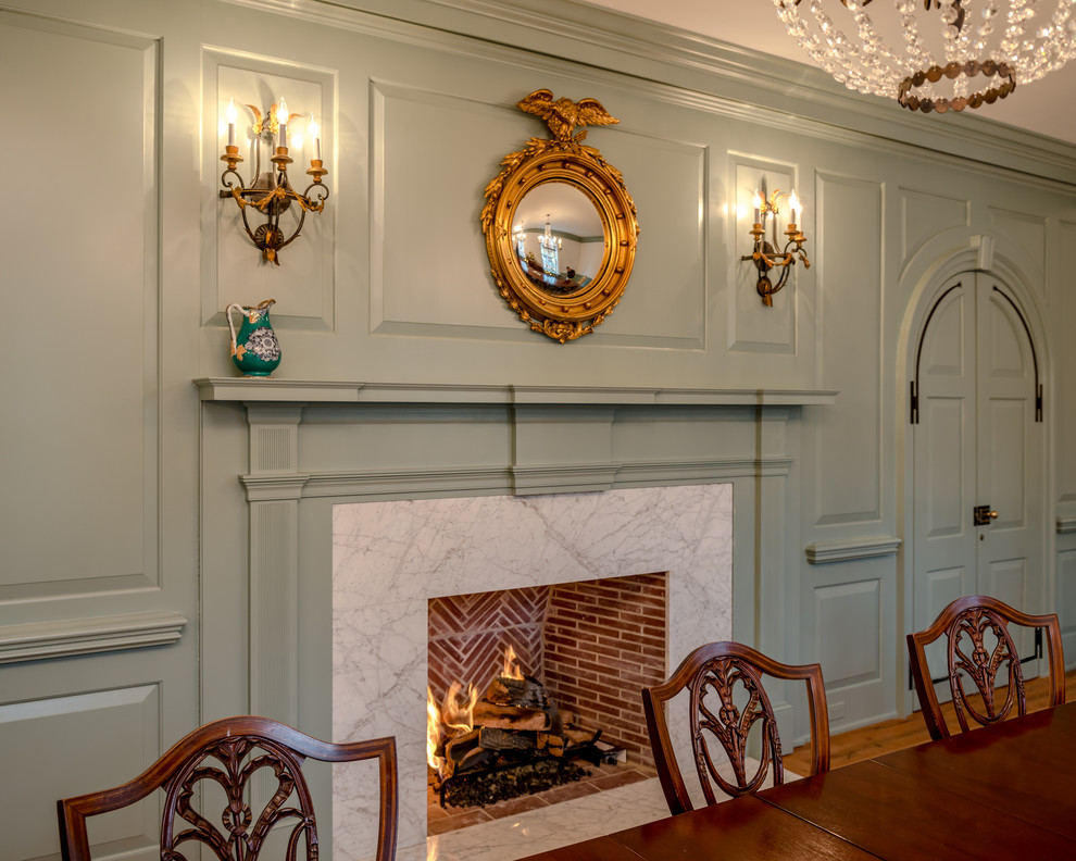 Exemple d'une grande salle à manger ouverte sur le salon chic avec un mur blanc, une cheminée standard, un manteau de cheminée en pierre et un sol en bois brun.