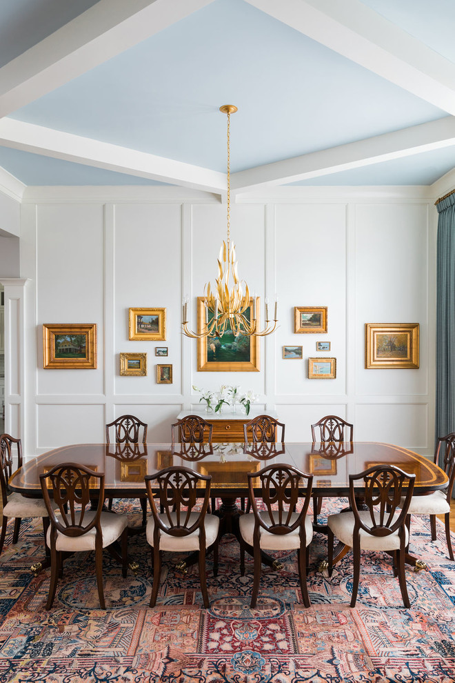 Immagine di una grande sala da pranzo aperta verso la cucina tradizionale con pareti bianche, pavimento in legno massello medio, nessun camino e pavimento marrone