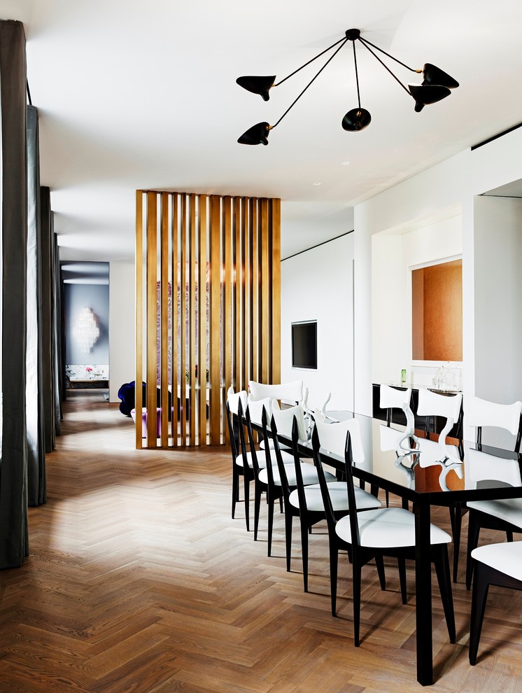 Réalisation d'une salle à manger design avec un mur blanc et un sol en bois brun.