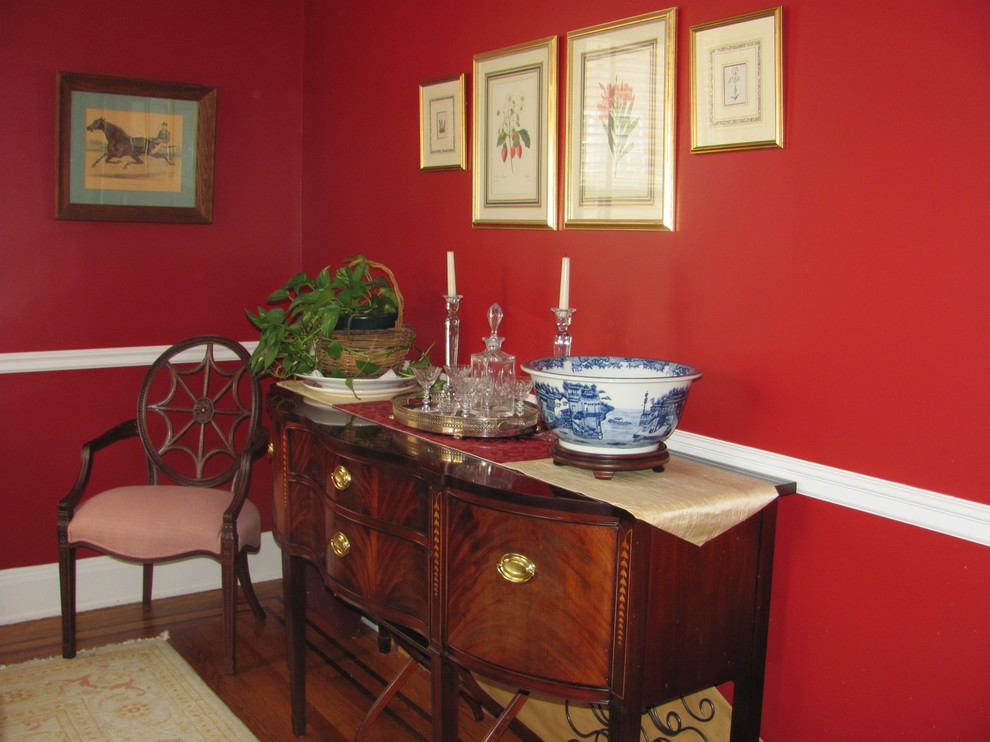 Aménagement d'une salle à manger classique fermée et de taille moyenne avec un mur rouge et parquet foncé.
