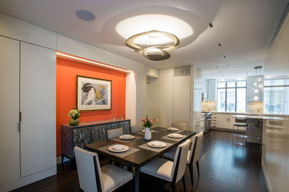 Cette image montre une salle à manger ouverte sur la cuisine design de taille moyenne avec un mur blanc et parquet foncé.