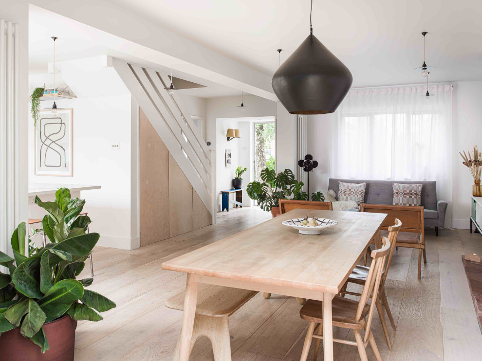 Foto de comedor escandinavo grande abierto con paredes blancas, suelo laminado, estufa de leña, marco de chimenea de ladrillo y suelo gris