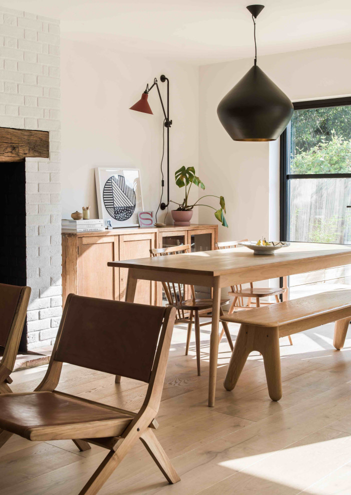 Photo of a large scandi open plan dining room in Essex with white walls, laminate floors, a wood burning stove, a brick fireplace surround and grey floors.