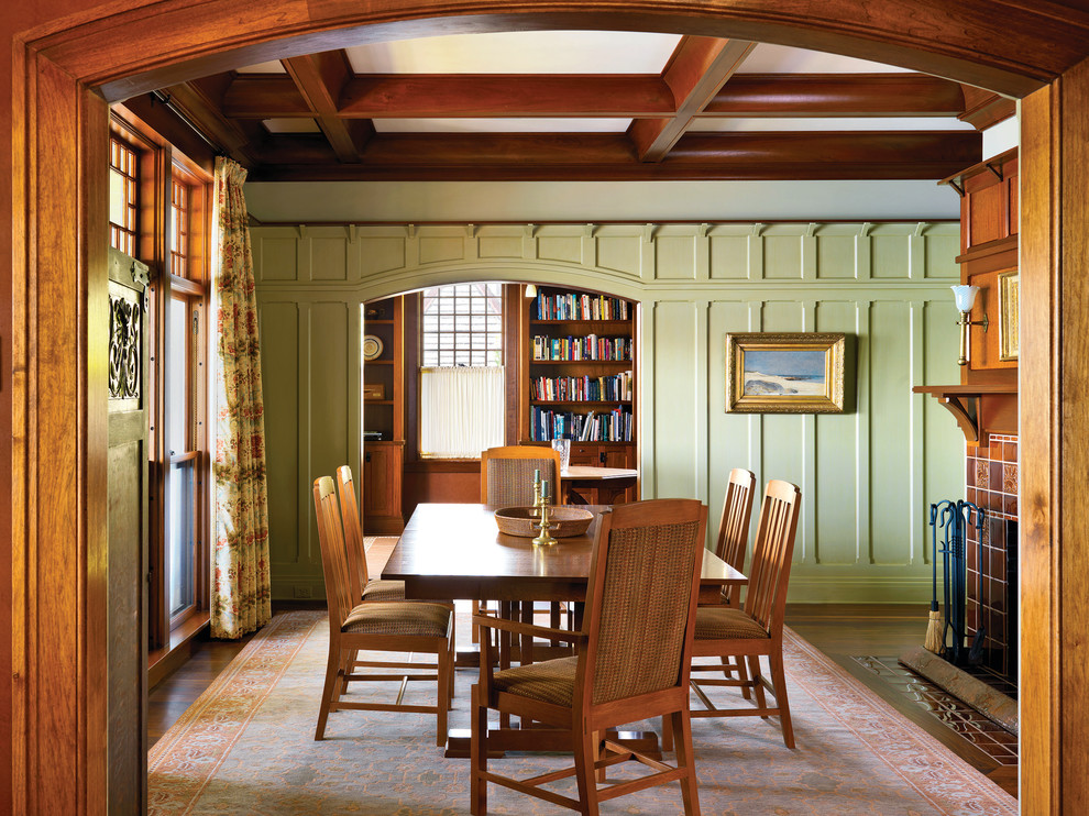 Cette image montre une salle à manger craftsman fermée avec un mur vert, parquet foncé, une cheminée standard et un manteau de cheminée en carrelage.