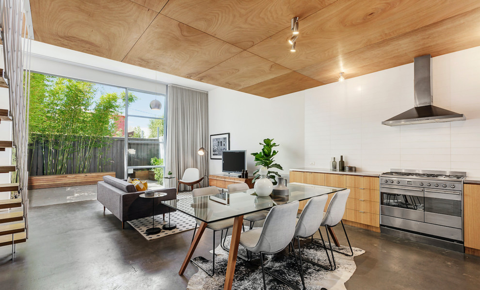 Esempio di una sala da pranzo aperta verso il soggiorno minimal di medie dimensioni con pareti bianche, pavimento in cemento e pavimento grigio