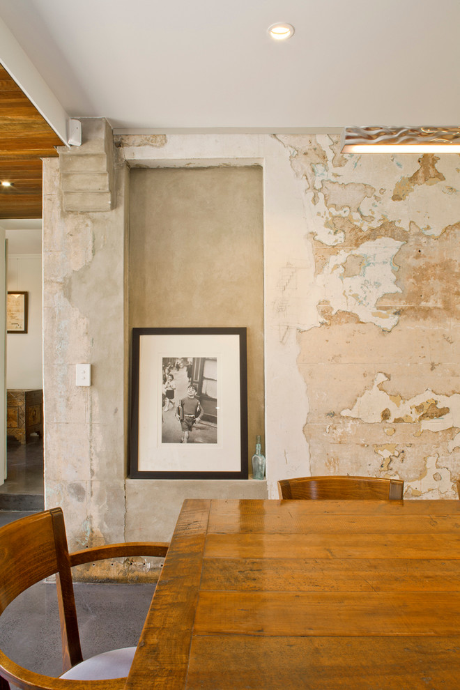 Réalisation d'une grande salle à manger ouverte sur la cuisine minimaliste avec un mur blanc et sol en béton ciré.
