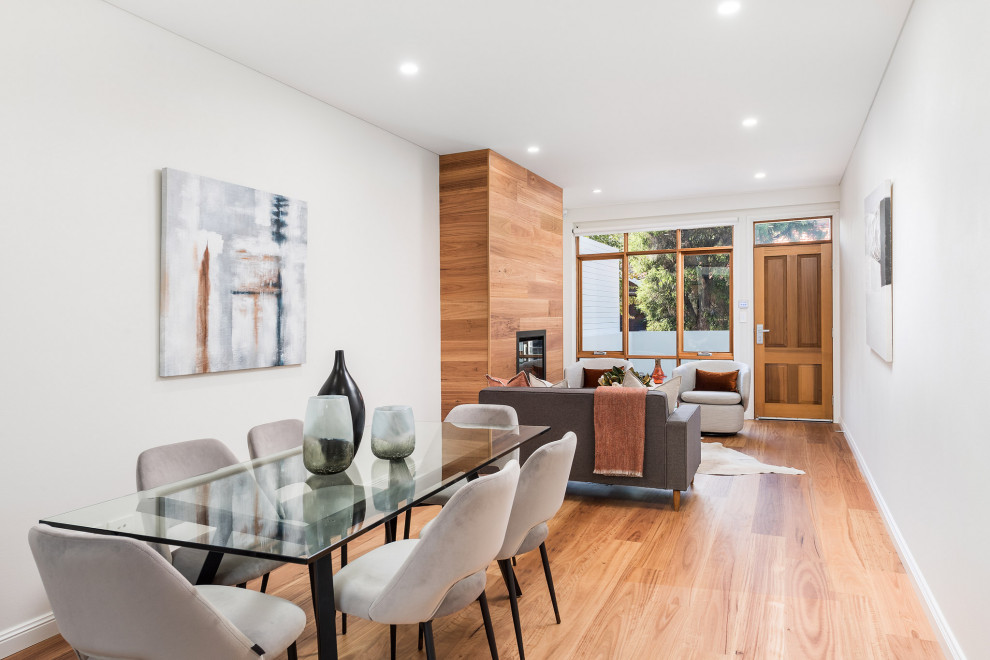 Idée de décoration pour une salle à manger ouverte sur le salon design de taille moyenne avec un mur gris, un sol en bois brun et un sol beige.
