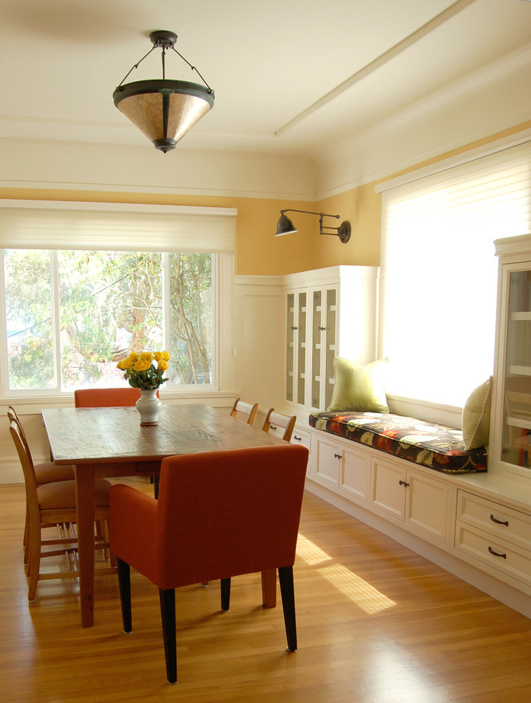 Idées déco pour une salle à manger classique de taille moyenne avec un mur jaune, un sol en bois brun, un sol beige et éclairage.