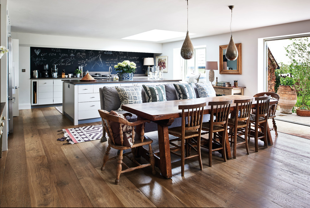 Immagine di una sala da pranzo aperta verso il soggiorno country con pareti bianche, parquet scuro e pavimento marrone