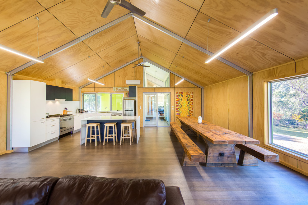 Aménagement d'une salle à manger ouverte sur la cuisine industrielle de taille moyenne avec un mur marron et un sol en bois brun.