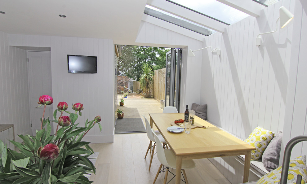 На фото: маленькая гостиная-столовая в морском стиле с белыми стенами и светлым паркетным полом без камина для на участке и в саду с