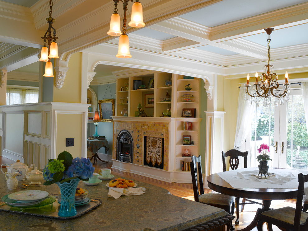 Exemple d'une grande salle à manger ouverte sur la cuisine victorienne avec un mur jaune, parquet clair, une cheminée standard et un manteau de cheminée en carrelage.