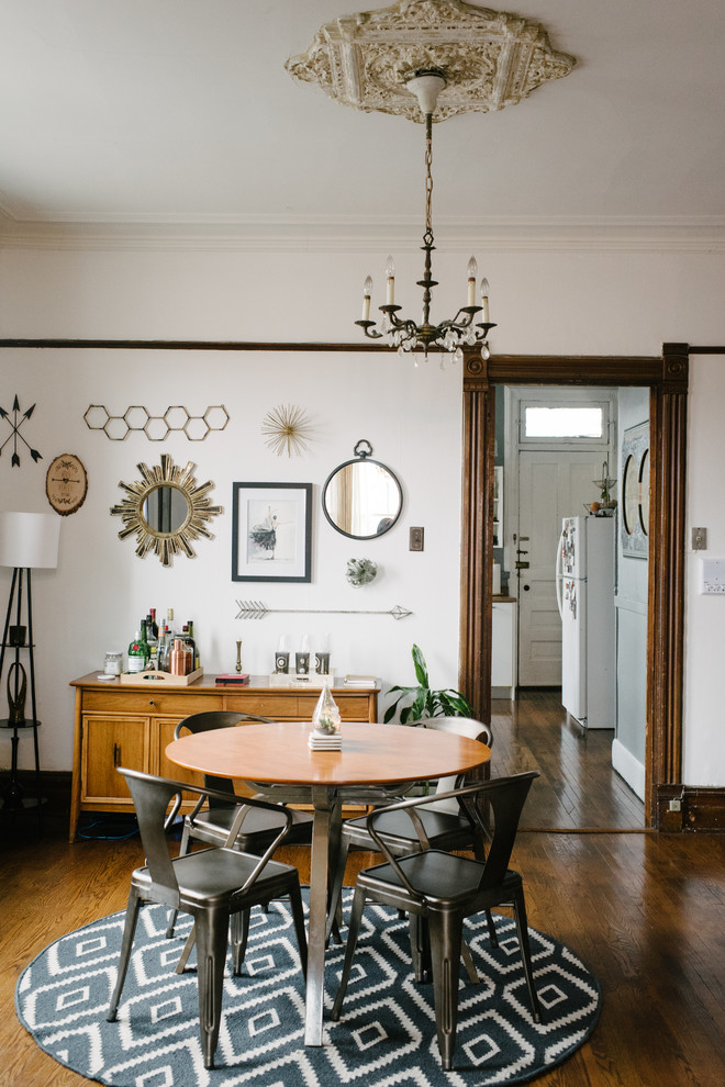 Aménagement d'une salle à manger éclectique avec un mur blanc et un sol en bois brun.