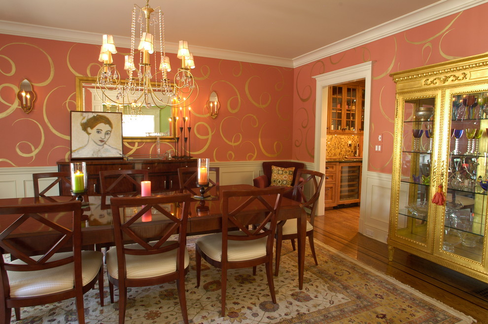 На фото: отдельная столовая в современном стиле с темным паркетным полом и розовыми стенами