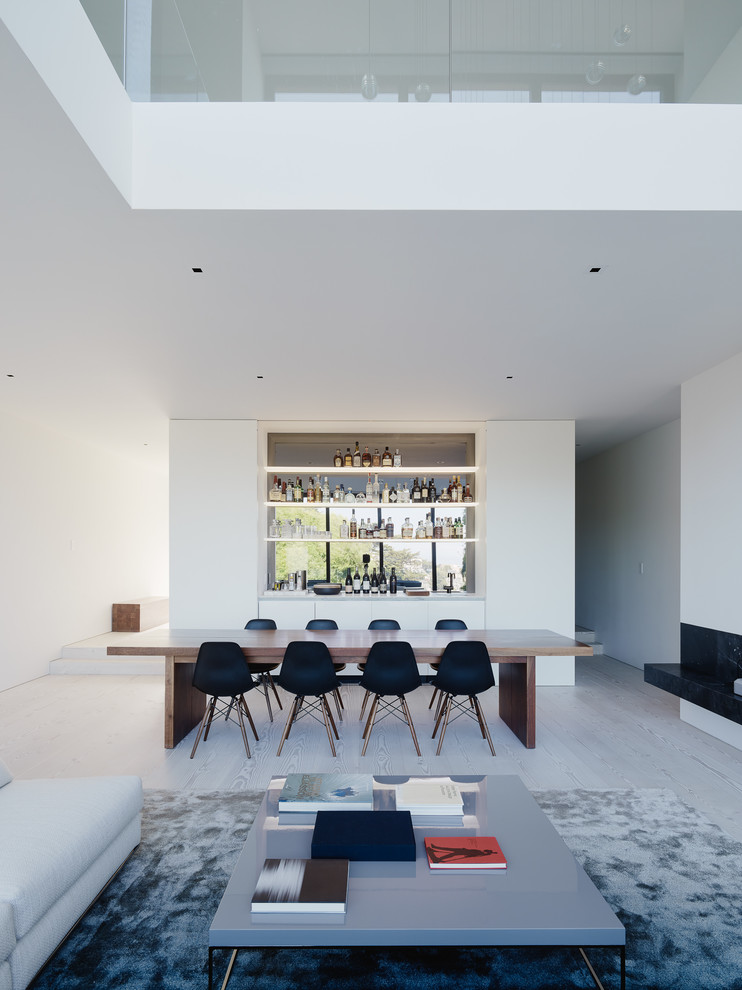 Источник вдохновения для домашнего уюта: столовая в стиле модернизм с белыми стенами, светлым паркетным полом, горизонтальным камином и серым полом