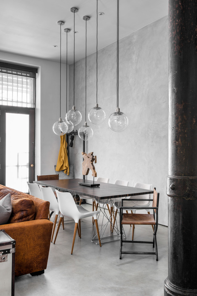 Immagine di una sala da pranzo aperta verso il soggiorno industriale con pareti grigie, pavimento in cemento e pavimento grigio