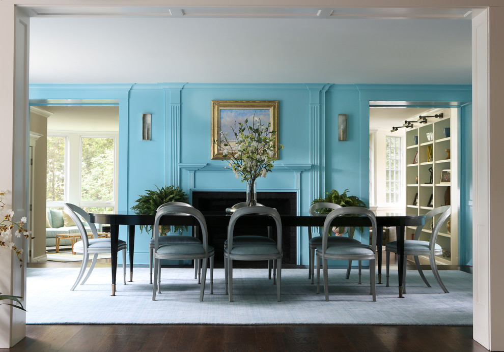 Klassisk inredning av en stor separat matplats, med blå väggar, mörkt trägolv, en standard öppen spis, en spiselkrans i trä och brunt golv