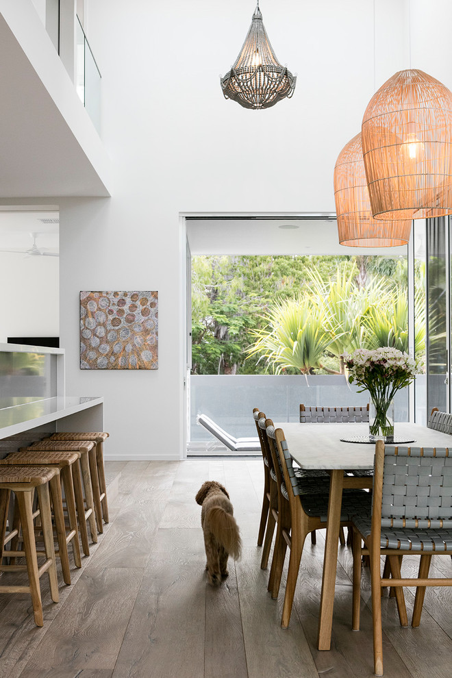 Idee per una sala da pranzo aperta verso la cucina stile marinaro con pareti bianche, parquet scuro e pavimento marrone