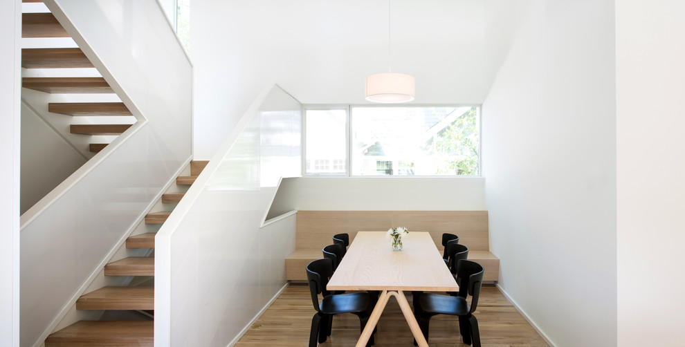 Immagine di una sala da pranzo aperta verso la cucina moderna con pareti bianche, parquet chiaro, nessun camino e pavimento marrone