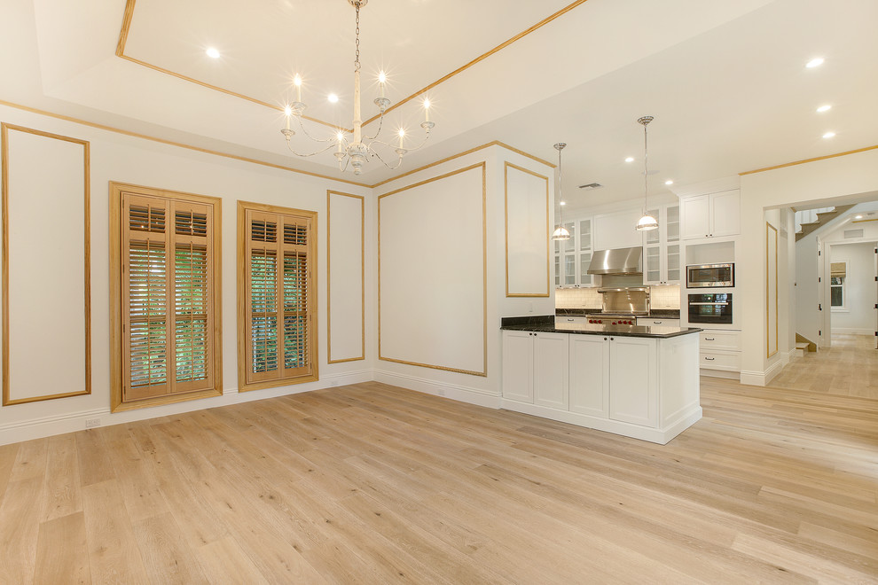 Idee per una sala da pranzo aperta verso la cucina stile marinaro di medie dimensioni con pareti bianche e parquet chiaro
