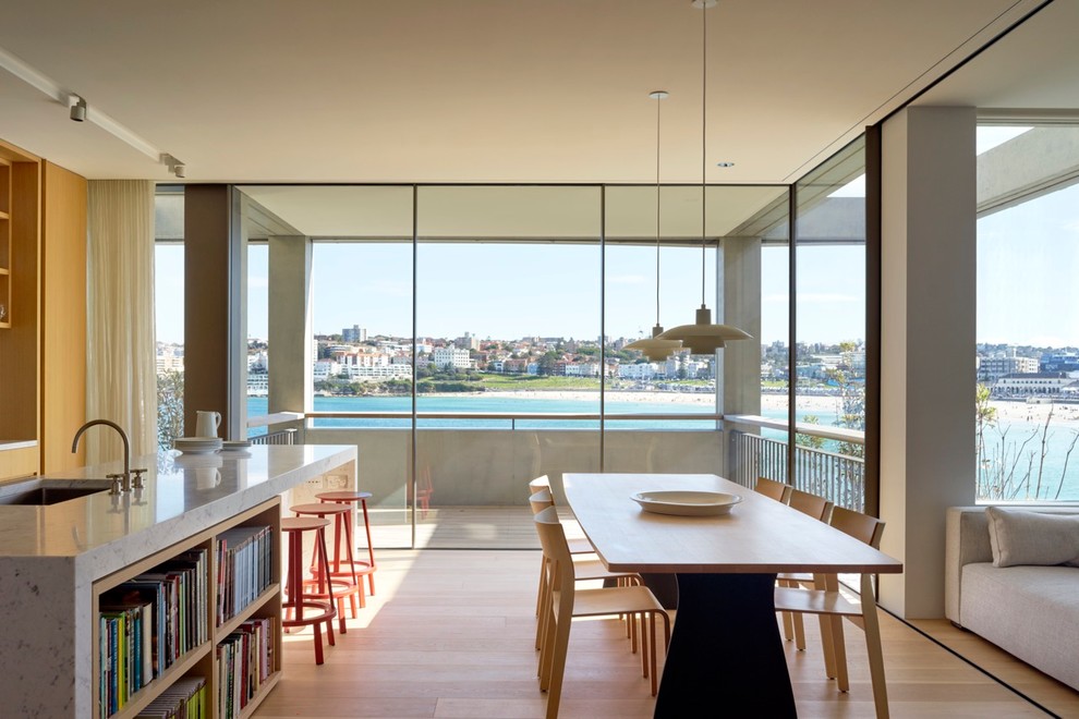 Immagine di una sala da pranzo aperta verso il soggiorno minimalista con parquet chiaro