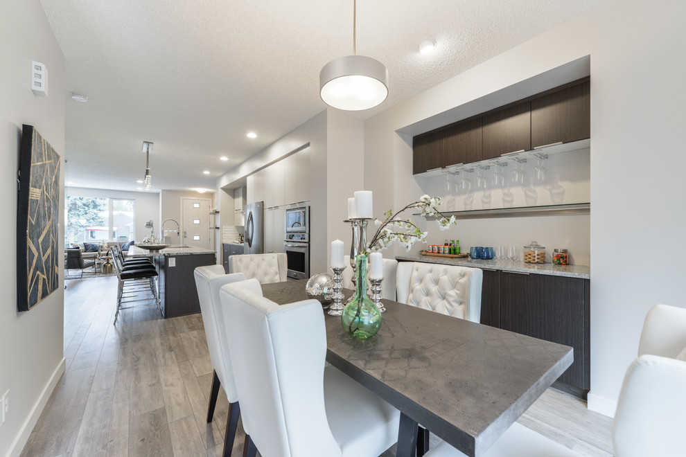 Ispirazione per una sala da pranzo aperta verso la cucina design di medie dimensioni con pareti bianche, pavimento in laminato e pavimento grigio