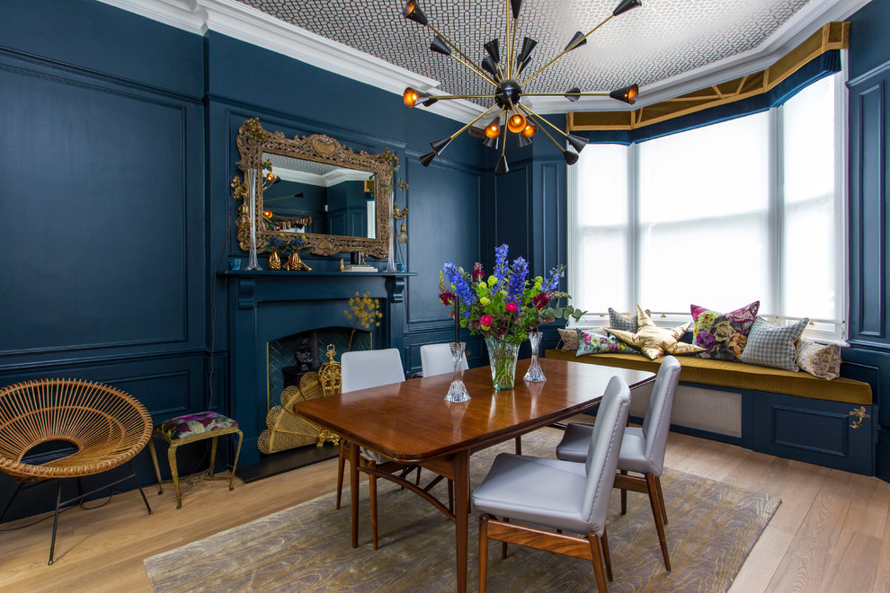 Geschlossenes Retro Esszimmer mit blauer Wandfarbe, braunem Holzboden, Kamin, Kaminumrandung aus Holz und braunem Boden in London