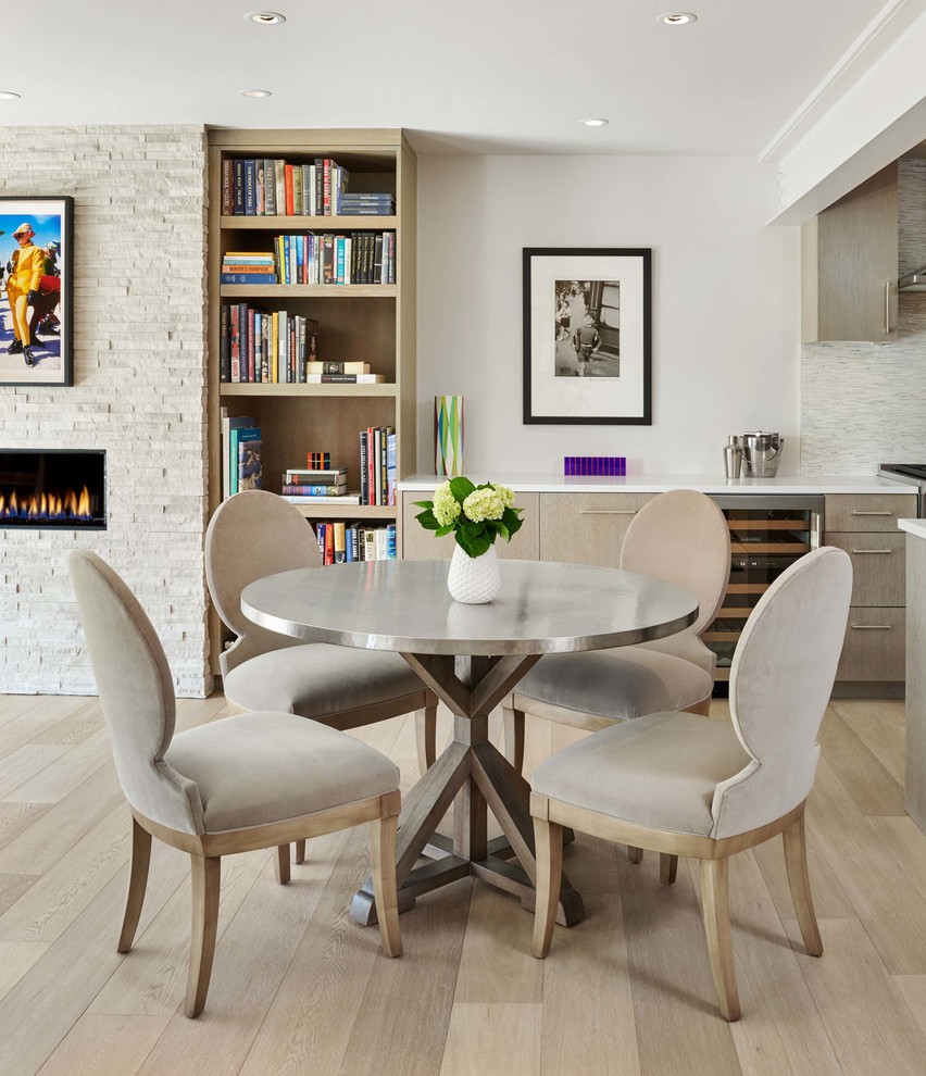 Cette image montre une petite salle à manger ouverte sur la cuisine minimaliste avec un mur gris, parquet clair, un sol beige, une cheminée ribbon et un manteau de cheminée en pierre.