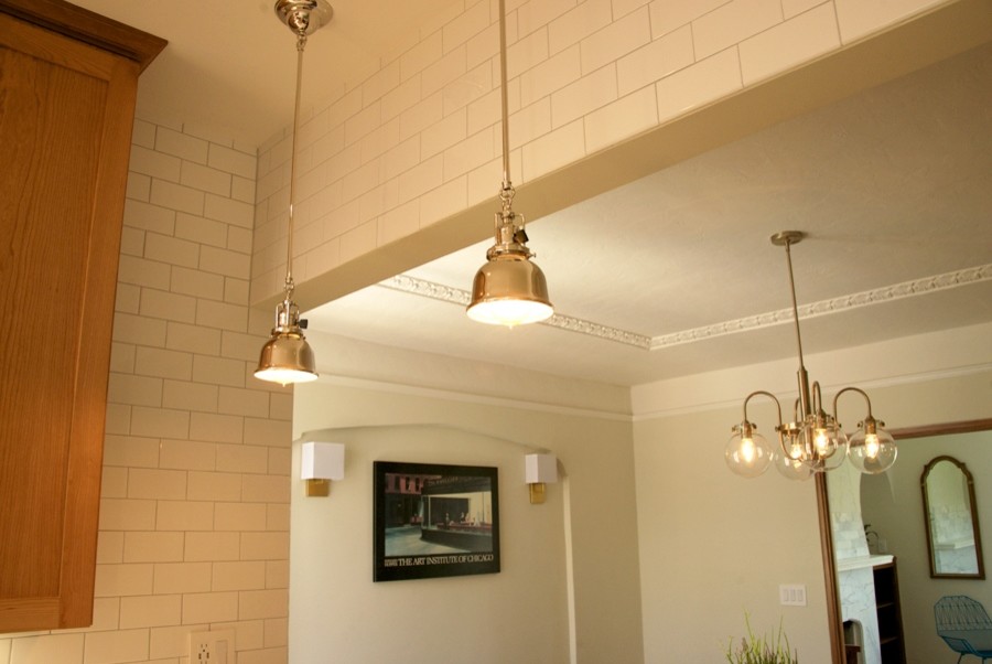 Cette image montre une salle à manger ouverte sur la cuisine traditionnelle de taille moyenne avec un mur blanc, un sol en bois brun, une cheminée standard et un manteau de cheminée en pierre.