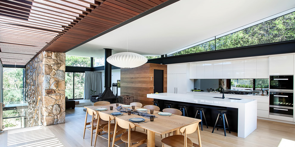 Cette image montre une salle à manger ouverte sur la cuisine design de taille moyenne avec un mur blanc et un sol en bois brun.