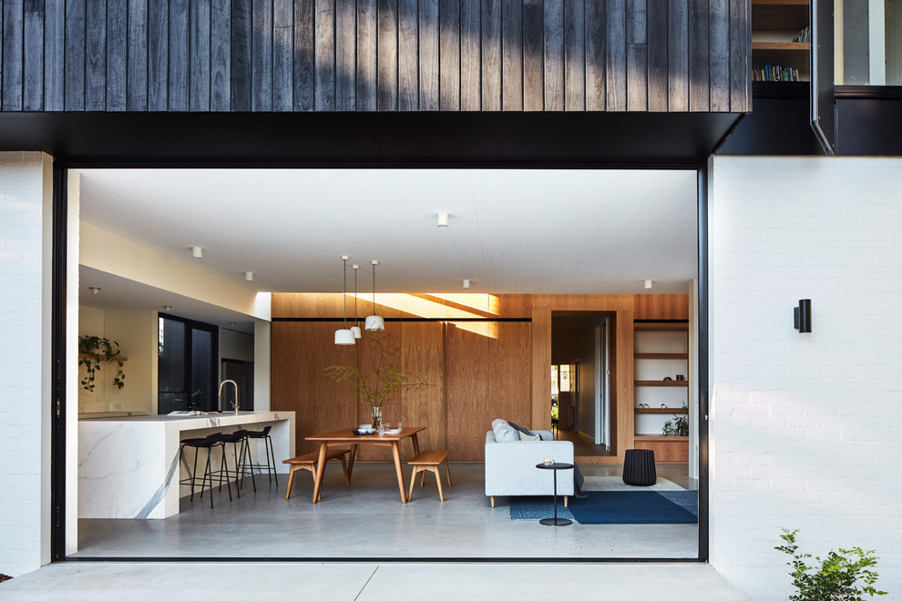 Offenes Modernes Esszimmer mit weißer Wandfarbe, Betonboden und grauem Boden in Melbourne