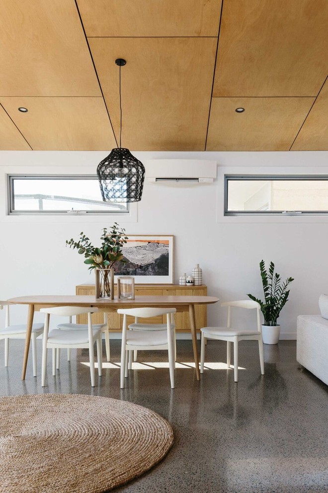 На фото: большая кухня-столовая в современном стиле с белыми стенами и бетонным полом с