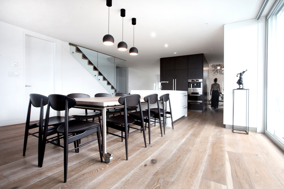 This is an example of a large modern kitchen/dining room in Sydney with white walls, medium hardwood flooring and no fireplace.