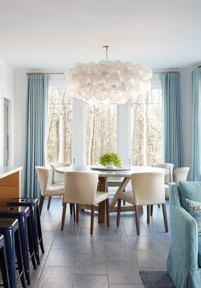 Immagine di una sala da pranzo aperta verso il soggiorno stile marino con pareti bianche e pavimento grigio