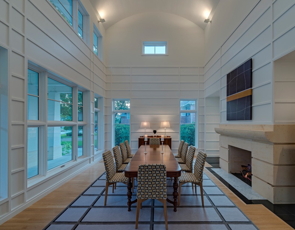 Inspiration pour une salle à manger minimaliste fermée et de taille moyenne avec un mur blanc, parquet clair, une cheminée standard et un manteau de cheminée en pierre.