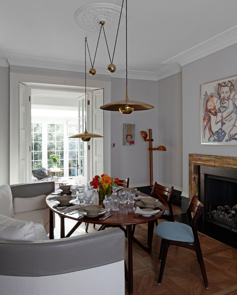 Mittelgroße Retro Wohnküche mit grauer Wandfarbe, braunem Holzboden, Kamin, Kaminumrandung aus Stein und braunem Boden in London