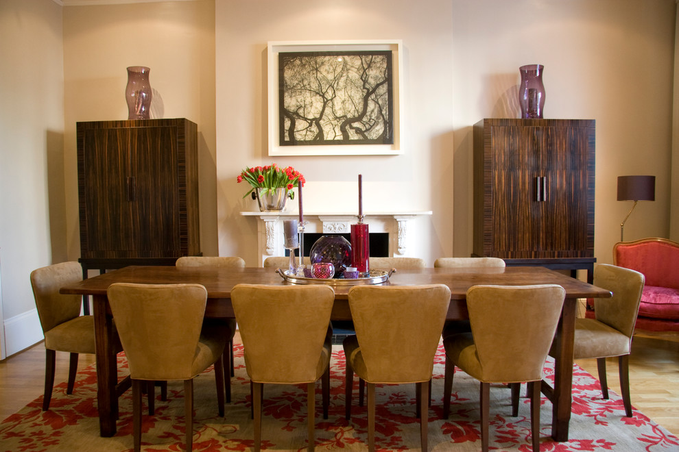 Example of a transitional dining room design in London with beige walls and a standard fireplace